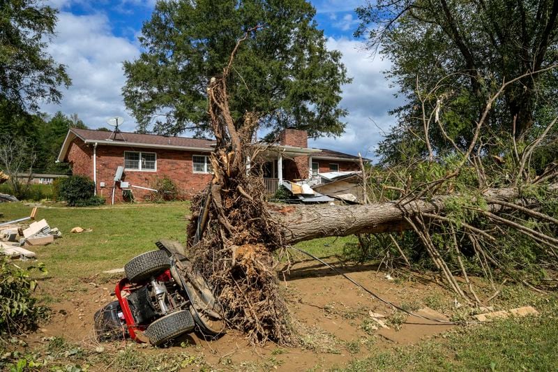 An overturned tractor lies next to an uprooted tree on the White family' property in the aftermath of Hurricane Helene, Tuesday, Oct. 1, 2024 in Morganton, N.C. The adjacent Catawba River flooded due to torrential rains destroying the seven of family's nine homes on the property. (AP Photo/Kathy Kmonicek)