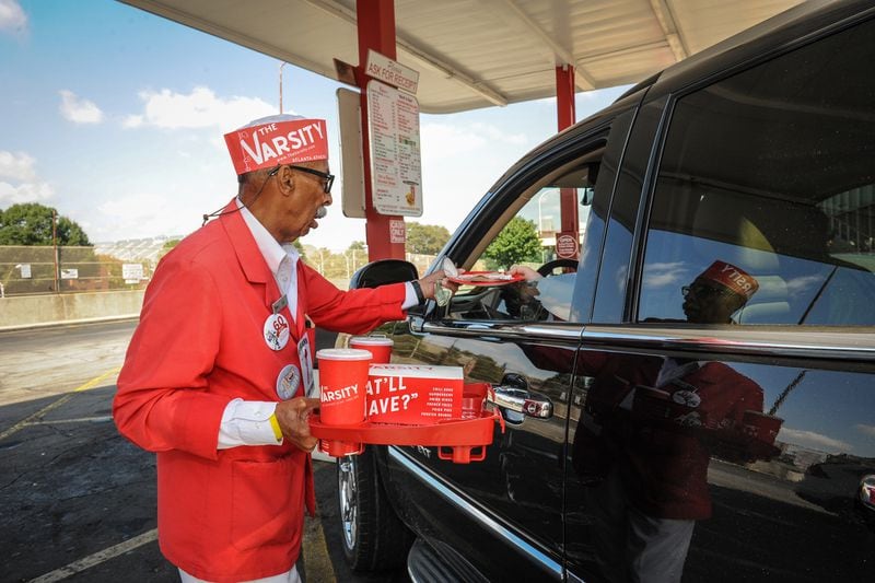 Wendell Brock reports on the Varsity and its history of food and scene in Atlanta on Tuesday October 13, 2015. Carhop Frank Jones, the longest employed carhop at the Varsity, hands a customer paper plates and napkins before hanging the food tray on his car window. Mr. Jones is 84 years old and has worked there on and off since 1949 and steady since December 1955. (Becky Stein Photography)