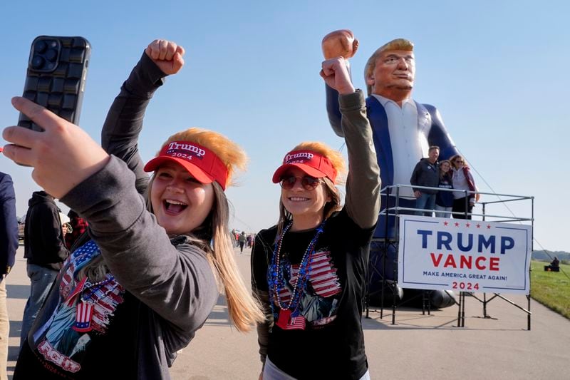 Faith Rail, right, and Kellie Kamphuis take a selfie in front of an inflatable of Republican presidential nominee former President Donald Trump before he speaks at a campaign stop at the Dodge County Airport Sunday, Oct. 6, 2024, in Juneau, Wis. (AP Photo/Morry Gash)