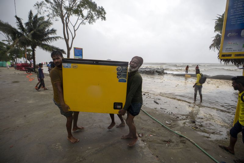 Men salvage a refrigerator as water flows on to the Kuakata beach on the coast of Bay of Bengal caused by the advancing Cyclone Remal in Barisal, Bangladesh, Sunday, May 26, 2024. (AP Photo/Abdul Goni)