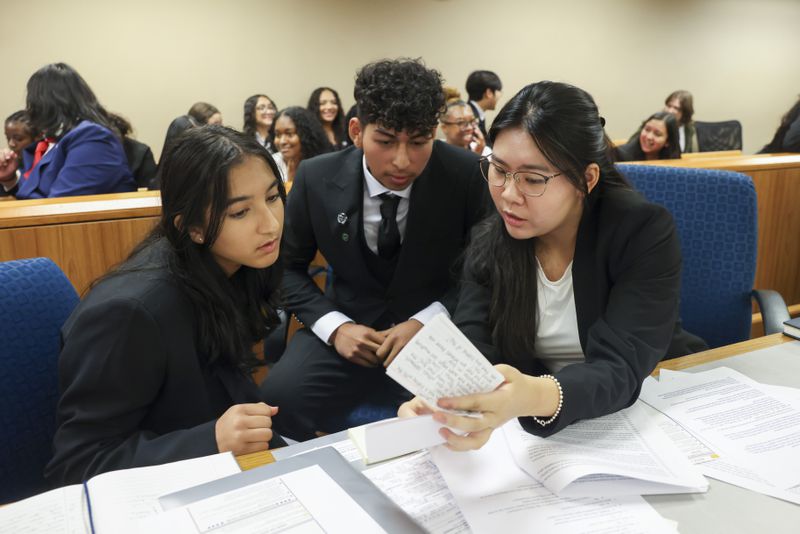 In a mock trial, the prosecution team of Neural Gandhi (left), William Pacheco (center) and Irene Kim discuss the case during the Junior District Attorney and Investigator Mentorship Program at the Gwinnett County Justice and Administration Center, Tuesday, June 25, 2024, in Lawrenceville. (Jason Getz / AJC)
