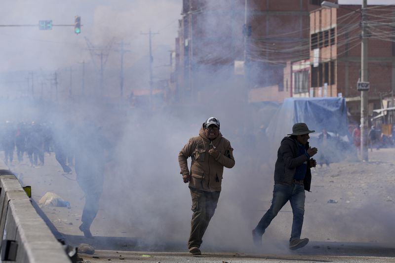 Supporters of former President Evo Morales run from tear gas thrown by police during clashes with supporters of current President Luis Arce during a march to La Paz, in El Alto, Bolivia, Sunday, Sept. 22, 2024. (AP Photo/Juan Karita)