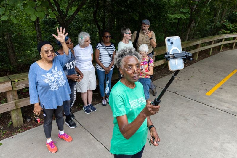 Carolyn Hartfield (center), leader of a walking group, closes out a walking session with in-person and virtual participants at Mason Mill park in Decatur. (Arvin Temkar / AJC)