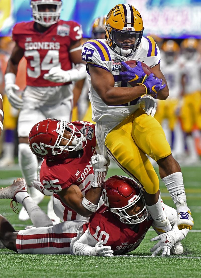 LSU running back Clyde Edwards-Helaire (22) gets tackled by Oklahoma's Justin Broiles (25) and Pat Fields (10) in the first half of the Chick-fil-A Peach Bowl at Mercedes-Benz Stadium on Saturday, December 28, 2019. (Hyosub Shin / Hyosub.Shin@ajc.com)