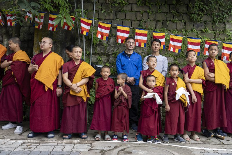 Novice Buddhist monks wait with ceremonial scarves to welcome Tibetan spiritual leader the Dalai Lama before he arrived in Dharamshala, India, Wednesday, Aug. 28, 2024. (AP Photo/Ashwini Bhatia)