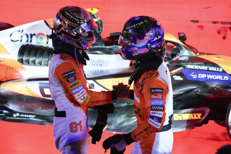 McLaren driver Lando Norris of Britain is congratulated by teammate Oscar Piastri, left, of Australia after winning the Singapore Formula One Grand Prix at the Marina Bay Street Circuit, in Singapore, Sunday, Sept. 22, 2024. (AP Photo/Vincent Thian)