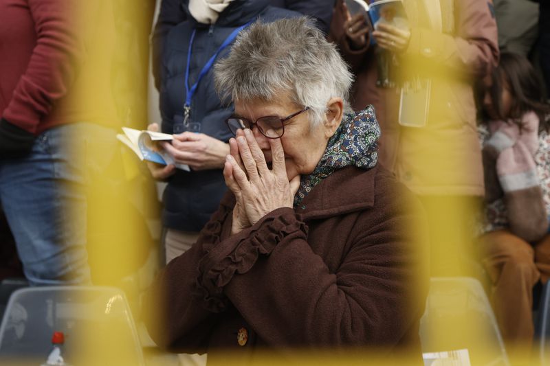 A faithful prays as Pope Francis presides the holy mass , at the King Baudouin stadium in Brussels, Belgium, Sunday, Sept. 29, 2024. (AP Photo/Omar Havana)