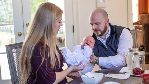 Katherine D’Alessandro passes her three-week-old son Dominic “Beatty” to her husband David D’Alessandro as they eat breakfast at their residence in Duluth. The couple moved from Boston to Georgia to live with David’s father, who is recently widowed. Now three generations live under one-roof nearly a year following the start of the COVID-19 pandemic in the United States. (Alyssa Pointer / Alyssa.Pointer@ajc.com)