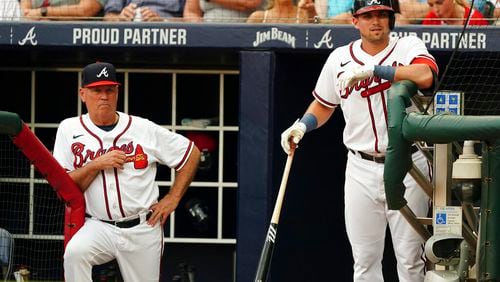 Braves manager Brian Snitker (left) and third baseman Austin Riley watch from the dugout during an August game. (AP Photo/John Bazemore)