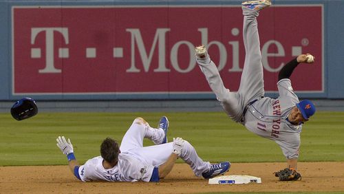 New York Mets shortstop Ruben Tejada falls after a slide by Los Angeles Dodgers' Chase Utley during the seventh inning of an NL Division Series baseball game Saturday, Oct. 10, 2015, in Los Angeles.