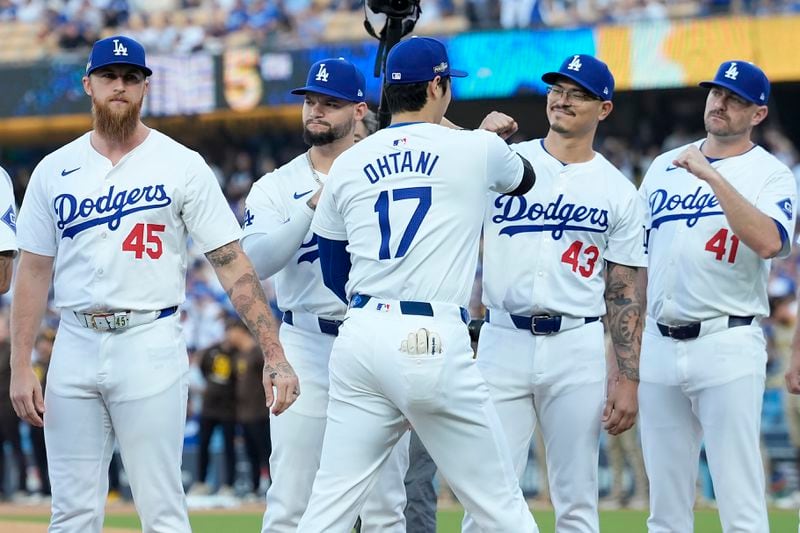 Los Angeles Dodgers' Shohei Ohtani (17) bumps fists with teammates before Game 1 of baseball's NL Division Series against the San Diego Padres, Saturday, Oct. 5, 2024, in Los Angeles. (AP Photo/Ashley Landis)