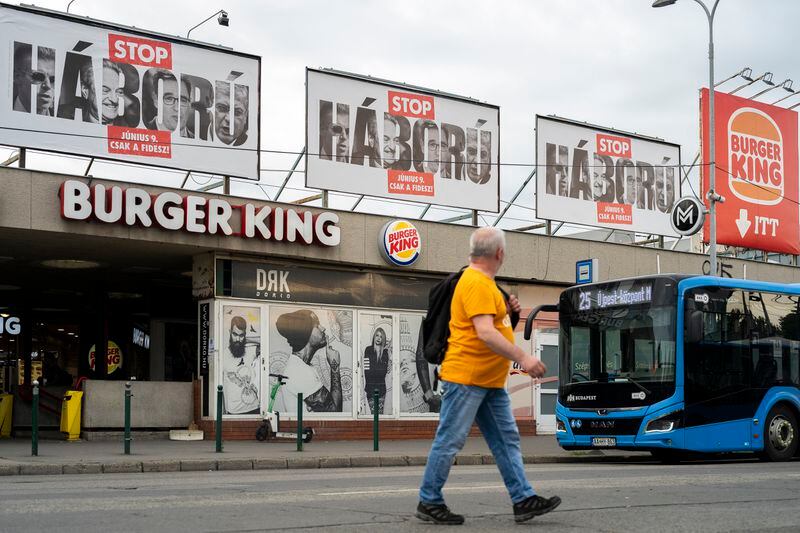 A man walks next to billboards with a message declaring "Stop War" have been erected on the streets of Budapest, Hungary, on May 21, 2024. A campaign message is unavoidable as thousands of billboards have been erected, featuring the faces of Péter Magyar, Budapest's liberal mayor, a former socialist prime minister and George Soros. (AP Photo/Denes Erdos)