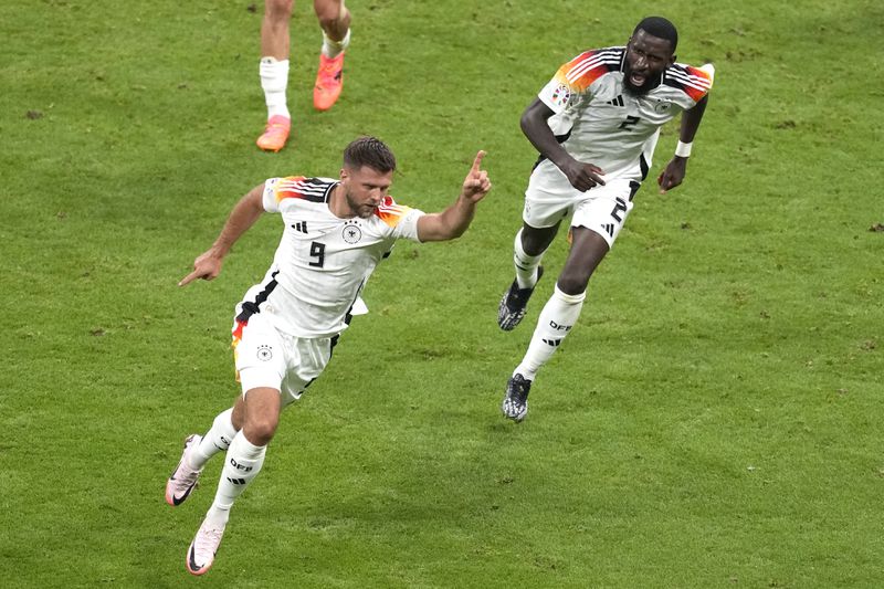Germany's Niclas Fuellkrug celebrates with Germany's Antonio Ruediger, right, after scoring his side's opening goal during a Group A match between Switzerland and Germany at the Euro 2024 soccer tournament in Frankfurt, Germany, Sunday, June 23, 2024. (AP Photo/Michael Probst)