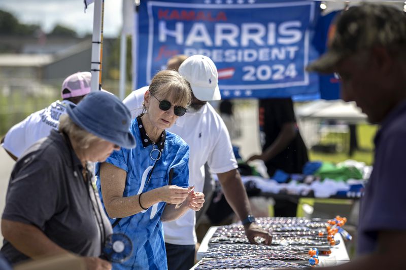 Cynthia Corey, from Brunswick, Ga., buys a Harris button from an vendor outside a venue where democratic presidential nominee Vice President Kamala Harris is planned to speak during a campaign event, Thursday, Aug. 29, 2024, in Savannah, Ga. (AP Photo/Stephen B. Morton)