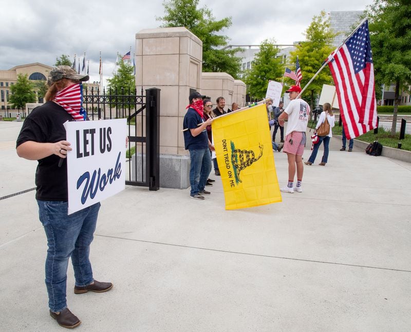 Protesters stand near the Capitol on April 24, 2020, to demand that businesses be allowed to reopen. That same day, Gov. Kemp loosened restrictions on gyms, nail salons, bowling alleys and many other businesses. (STEVE SCHAEFER / SPECIAL TO THE AJC)