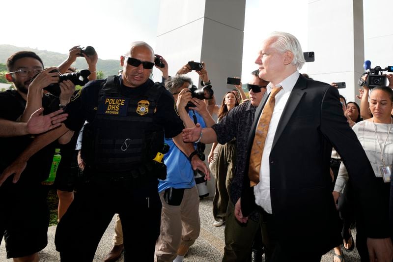 WikiLeaks founder Julian Assange, right, arrives, surrounded by the the media, at the United States courthouse where he is expected enter a plea deal, in Saipan, Mariana Islands, Wednesday, June 26 2024. (AP Photo/Eugene Hoshiko)