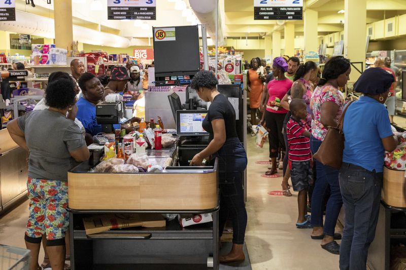 Costumers purchase groceries ahead of Hurricane Beryl in Arnos Vale, St. Vincent and the Grenadines, Sunday, June 30, 2024. (AP Photo/Lucanus Ollivierre)