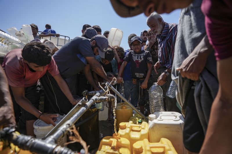 Displaced Palestinians line up to collect water, in Deir al Balah, central Gaza Strip, Friday, Aug. 23, 2024. (AP Photo/Abdel Kareem Hana)