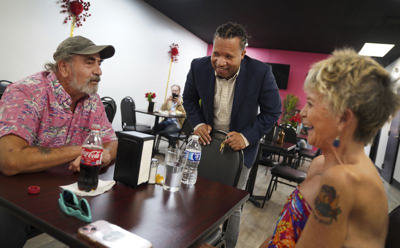 Karl Mattila, left, and his wife Linda, of Medway, Ohio, talk with Haitian and longtime Springfield resident Jacob Payen at Rose Goute Creole Restaurant in Springfield, Ohio, Monday, Sept. 16, 2024. (AP Photo/Jessie Wardarski)