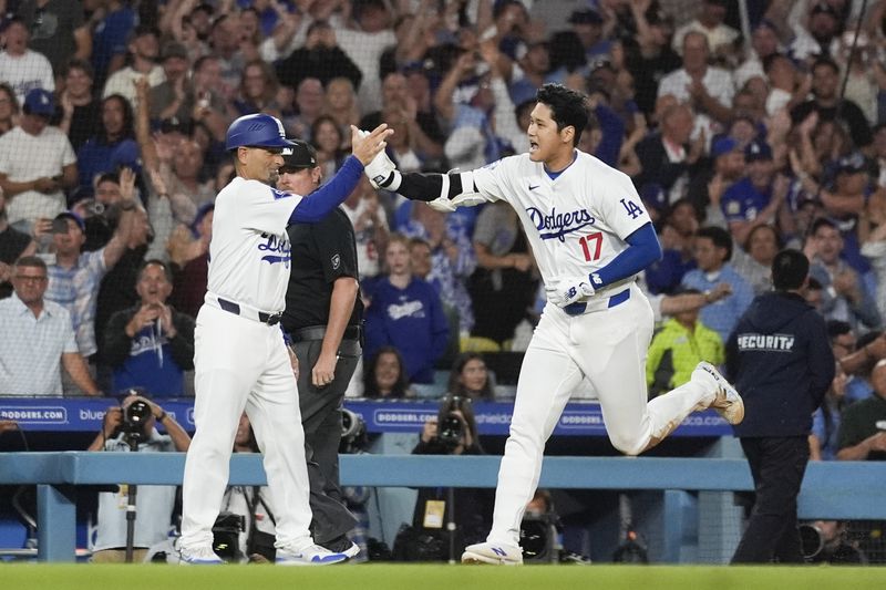 Los Angeles Dodgers designated hitter Shohei Ohtani (17) greets third base coach Dino Ebel as he runs the bases after hitting a grand slam during the ninth inning of a baseball game against the Tampa Bay Rays in Los Angeles, Friday, Aug. 23, 2024. The Dodgers won 7-3. Will Smith, Tommy Edman, and Max Muncy also scored. (AP Photo/Ashley Landis)