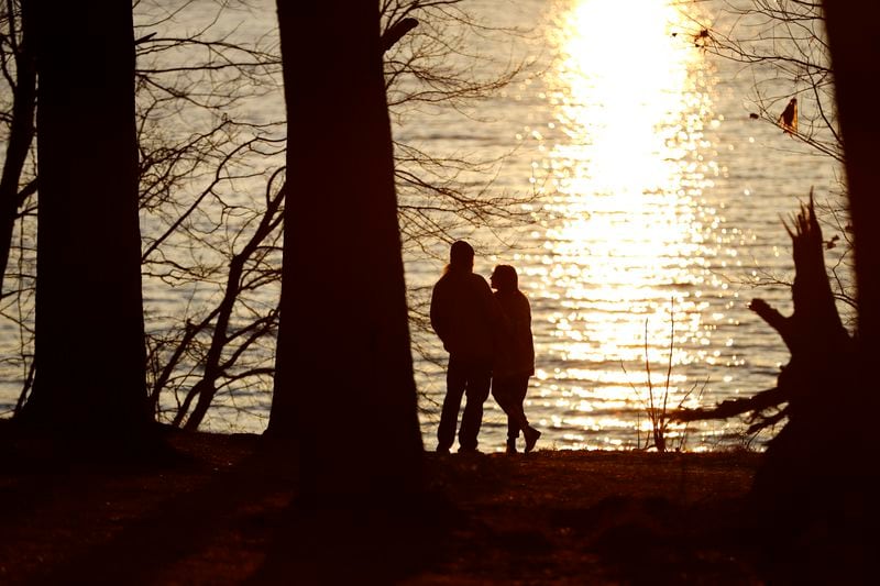 FILE - A couple stands at the banks of the Loch Raven Reservoir as the sun begins to set, Feb. 19, 2020, in Glen Arm, Md. (AP Photo/Julio Cortez, File)