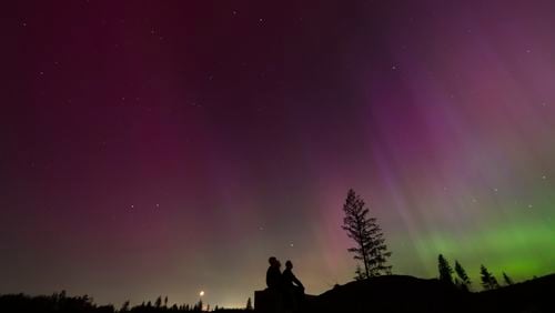 FILE - In this image taken with a long exposure, people look at the night sky towards the northern lights, or Aurora Borealis, May 10, 2024, in Estacada, Ore. (AP Photo/Jenny Kane, File)