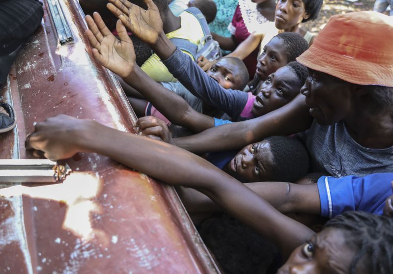 People displaced by armed attacks receive food from a nongovernmental organization in Saint-Marc, Haiti, Sunday, Oct. 6, 2024. (AP Photo/Odelyn Joseph)