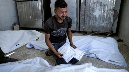 A Palestinian man mourns his 4-day-old twin relatives, killed in the Israeli bombardment of the Gaza Strip, as he holds their birth certificates, at a hospital morgue in Deir al-Balah, Tuesday, Aug. 13, 2024. (AP Photo/Abdel Kareem Hana)