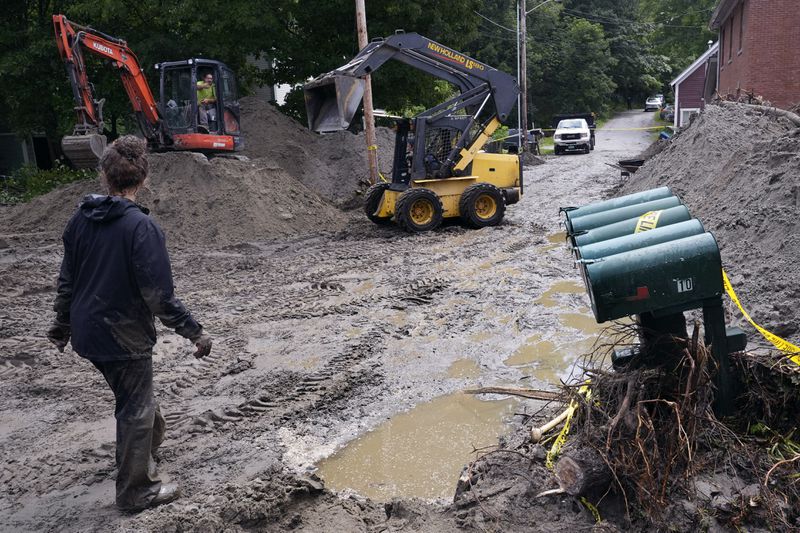 An excavator and loader clear Hudson Avenue of mud after remnants of Hurricane Beryl caused flooding and destruction, Friday, July 12, 2024, in Plainfield, Vt. (AP Photo/Charles Krupa)