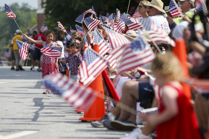 In this AJC file photo, Fourth of July parade goers in Marietta wave flags.