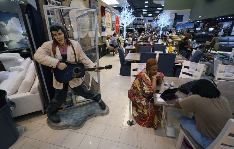 Houston residents Janice Taylor, left, and her daughter Janell spend time at Gallery Furniture, which is being used as a temporary shelter, to cool off and charge their electronic devices, in Houston, Tuesday, July 9, 2024. The effects of Hurricane Beryl left most in the area without power. (AP Photo/Eric Gay)
