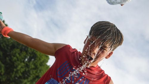 Jake Bearden, 14, from Lawrenceville, (right), cools off after running from the race on Piedmont Park during the 55th Peachtree Road Race in Atlanta on Thursday, July 4, 2024.  (Ziyu Julian Zhu / AJC)