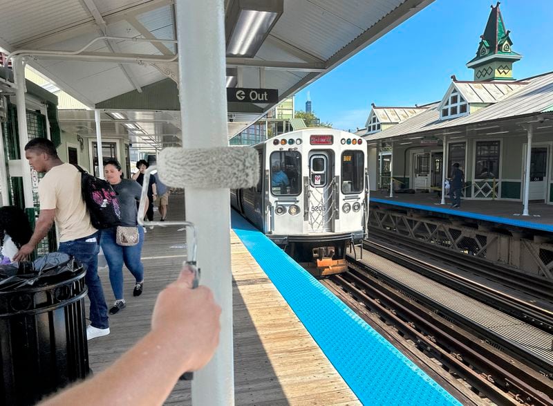 A Chicago Transit Authority employee paints a post at the Ashland Ave. station Sunday, Aug. 4, 2024, near the United Center where the Democratic National Convention will convene Monday, August 19, in Chicago. (AP Photo/Charles Rex Arbogast)