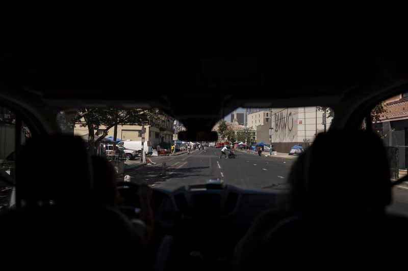 Maria McAfee, left, Wesley Health Centers' clinic director, drives a van through the Skid Row area of Los Angeles, Tuesday, Aug. 27, 2024. (AP Photo/Jae C. Hong)