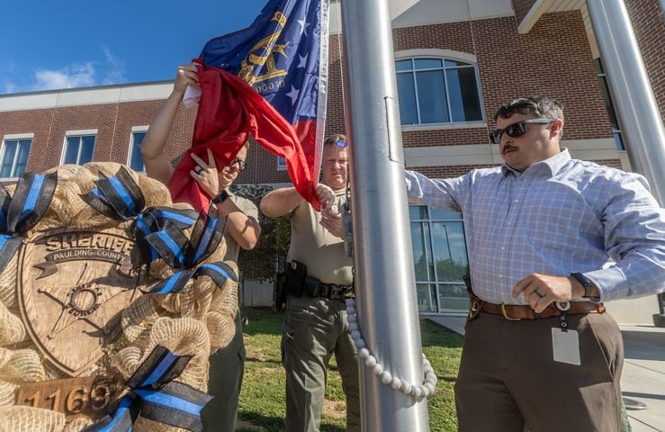 (Left to right) Paulding County Sheriff Sgt J. Gunter, Lt R. Gravett and Detective S. Raybon replace the Georgia State flag to fly at half staff in front of the Paulding county Sheriff’s office. (John Spink/AJC)