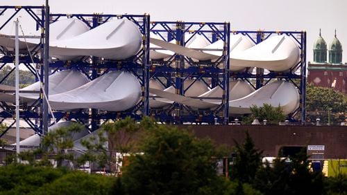 FILE - Giant wind turbine blades for the Vineyard Winds project are stacked on racks in the harbor, July 11, 2023, in New Bedford, Mass. The maker of a massive wind turbine blade that broke apart off Nantucket Island and washed up on the beaches says a manufacturing problem was responsible. (AP Photo/Charles Krupa, File)