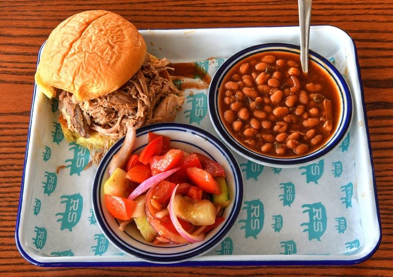 Pulled Pork Sandwich, with sides of baked beans and tomato cucumber salad (a seasonal offering), at Rodney Scott's Whole Hog BBQ in Atlanta. (Chris Hunt for The Atlanta Journal-Constitution)