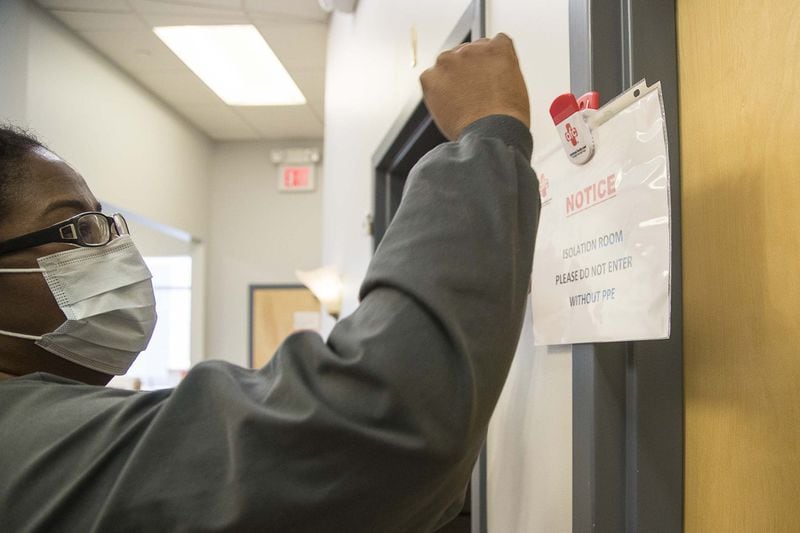 Kay Hayes (left), office manager at American Family Care, places an “isolation room” sign on a door during a mock-coronavirus training at the American Family Care urgent care clinic located inside the Piedmont West Outpatient Center in Atlanta, Tuesday. (ALYSSA POINTER/ALYSSA.POINTER@AJC.COM)