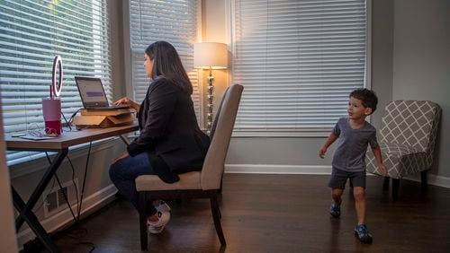 Turner Beeson (right) sneaks in the background as his mother, Sarah Beeson, Democratic candidate for State Senate District 56, prepares for a virtual campaign event at their residence in Roswell on Sept. 10, 2020. Turner usually spends time in the basement with his father and his little brother while Sarah is participating in virtual campaign events at night. (Alyssa Pointer / Alyssa.Pointer@ajc.com)