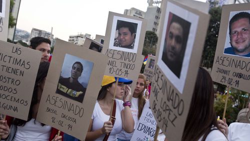 FILE - Demonstrators holds cardboard posters showing images of family and friends killed during anti-government protests, in Caracas, Venezuela, March 18, 2014. An Argentine federal court in Buenos Aires on June 28, 2024, concluded testimony from Venezuelan victims as part of an investigation into human rights abuses committed by security forces during the 2014 clamp down on mass anti-government protests. (AP Photo/Esteban Felix, File)