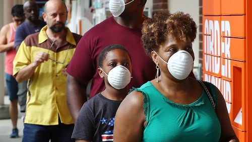 Customers wait in line to enter the Home Depot store at Midtown Place in March. Among retailers, Costco and Whole Foods have taken the lead in requiring customers to wear masks to shop, while others leave it up to the customer to decide. Curtis Compton ccompton@ajc.com