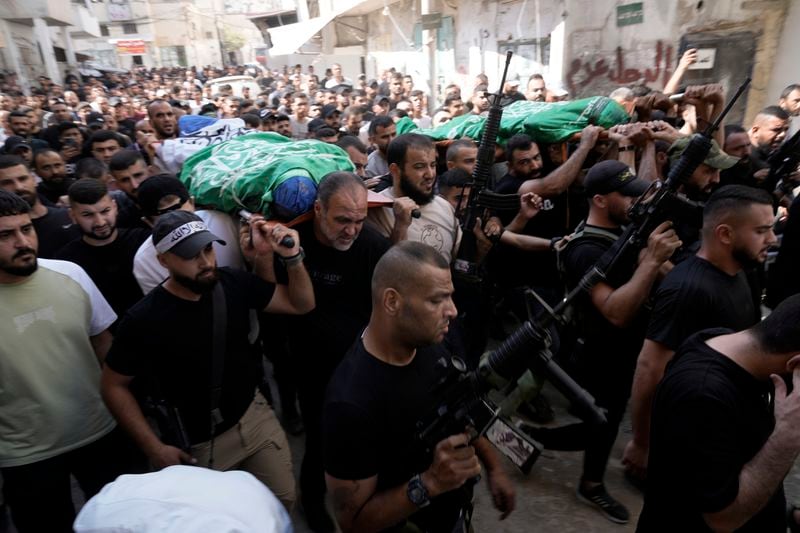 Mourners march during a funeral with the bodies of Palestinians Ahmed Abu Arra from the town of Aqaba, left, and Raafat Dawasa from the town of Silat Al-Harithiya, both draped in the Hamas flag and killed in an Israeli strike in the Jenin refugee camp, in the West Bank city of Jenin, Sunday, Aug. 18, 2024. Israel's military said Saturday it struck a "terrorist cell" in Jenin. The Palestinian health ministry there said two bodies were taken to a government hospital; Hamas claimed the two men as commanders in its military wing.(AP Photo/Majdi Mohammed)