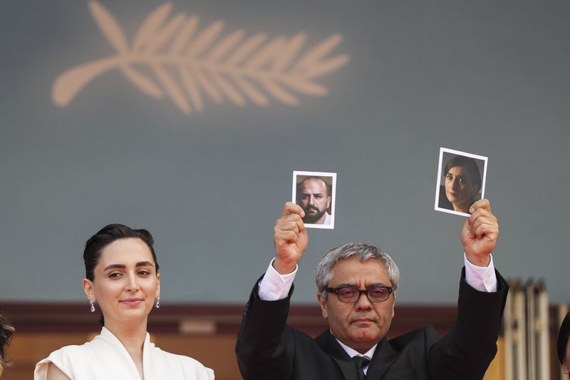 Director Mohammad Rasoulof, right, holds up photographs, alongside Soheila Golestani, left, upon arrival at the premiere of the film 'The Seed of the Sacred Fig' at the 77th international film festival, Cannes, southern France, Friday, May 24, 2024. (Photo by Scott A Garfitt/Invision/AP)