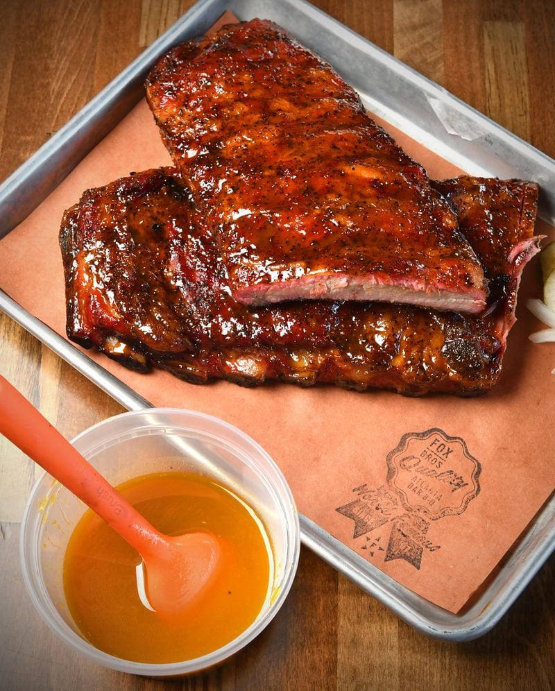 240620 Brookhaven, Ga: Brookhaven Rib Glaze and a rack of baby back ribs from Fox Bros. BBQ, photographed in the Brookhaven Fox Bros. location. Brothers Jonathan and Justin (glasses) co-owners of Atlanta-based Fox Brothers Barbecue, show how to use their ÒBrookhaven Rib GlazeÓ - (note the glazeÕs title may change according to Jonathan Fox) on a rack of BBQ Baby Back Ribs at their newly opened Brookhaven location, 4058 Peachtree Road, Brookhaven Ga. 30319. Photo for AJC Food section story on Marinades, by C.W. Cameron. Photos taken Thursday June 20, 2024. Food styling by Jonathan and Justin Fox. 071424MARINADES (CHRIS HUNT FOR THE ATLANTA JOURNAL-CONSTITUTION)