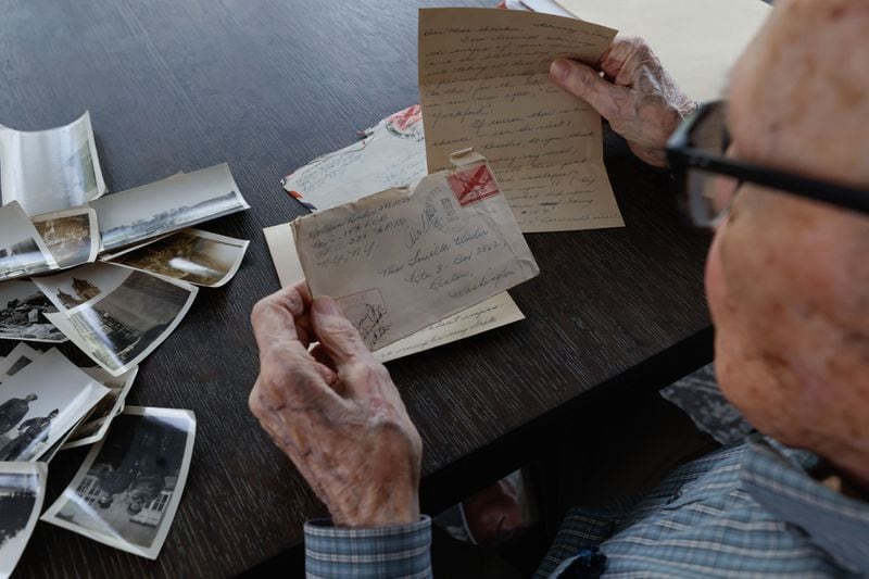 Alan Kinder looks through old photos and letters he wrote to loved ones. Kinder, along with other WWII veterans, will visit Normandy for the commemoration of the 80th anniversary of D-Day in June. ( Natrice Miller/ AJC)