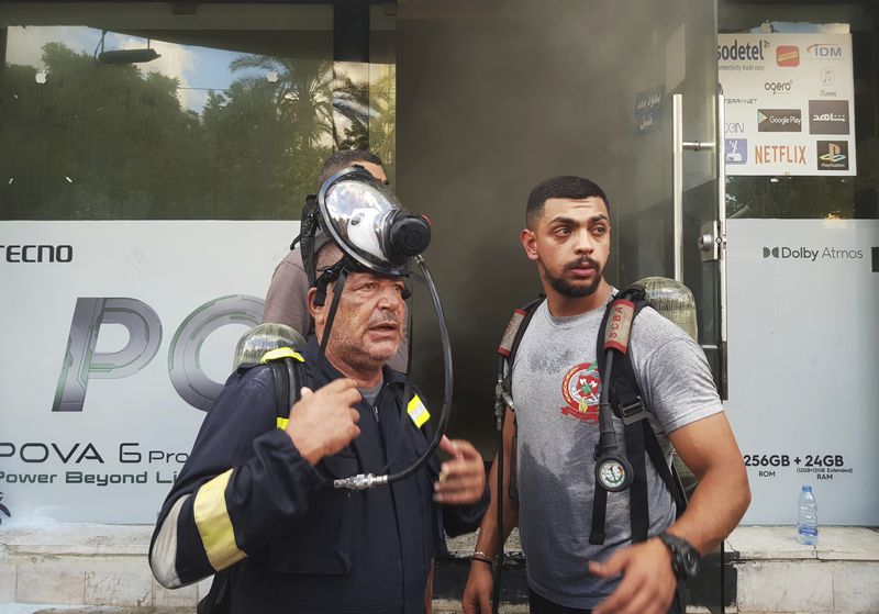 FILE - Firefighters stand outside a damaged mobile shop after what is believed to be the result of a walkie-talkies exploding inside it, in the southern port city of Sidon, Lebanon, Wednesday, Sept. 18, 2024. (AP Photo/Mohammed Zaatari, File)