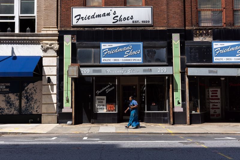 A pedestrian walks by Friedman’s Shoes in Atlanta on Wednesday, July 31, 2024. (Arvin Temkar / AJC)