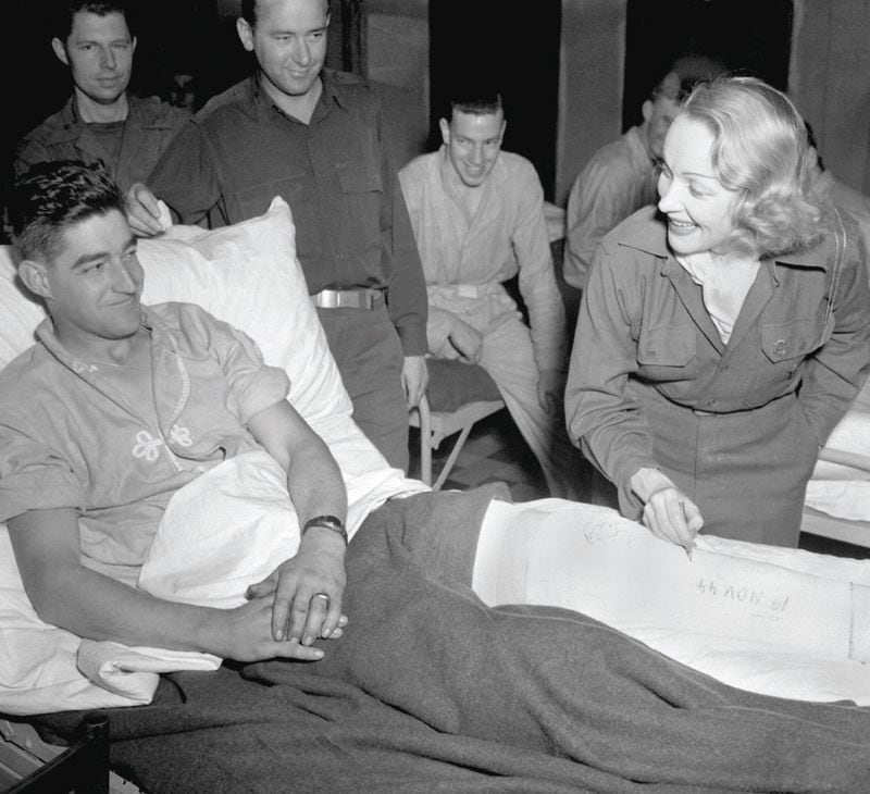 Marlene Dietrich signs a wounded serviceman’s cast in Belgium in November 1944. Courtesy of Everett Collection, Inc.