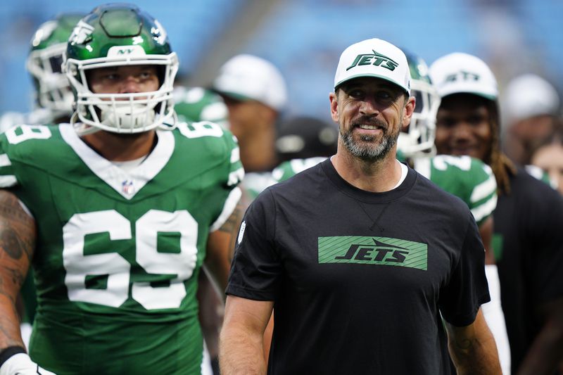 New York Jets quarterback Aaron Rodgers, right, walks on the field with teammates before a preseason NFL football game against the Carolina Panthers, Saturday, Aug. 17, 2024, in Charlotte, N.C. (AP Photo/Jacob Kupferman)