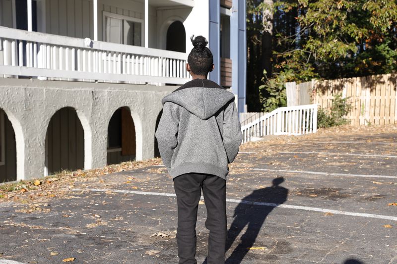 Stacie Jackson’s 10-year-old son, who she didn't want identified in this article, stands in the parking lot of their apartment complex in south Fulton County on Wednesday, Nov. 1, 2023. Their apartment, the only one she says she can afford, has been the site of more than 257 crimes including three homicides since they moved in a decade ago.